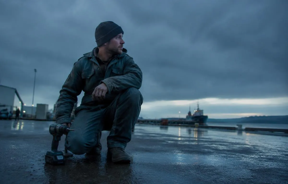 Tradesperson using a cordless driver at a rainy dawn